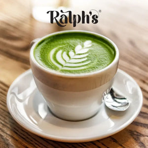Matcha latte with leaf latte art in a white cup on wooden table, plant-based drink at iPlantBased UAE