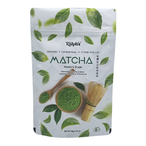 Ralph’s organic ceremonial matcha powder pouch with wooden spoon, bowl, tea whisk, and green leaves