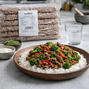 Bowl of ground meat with vegetables on rice, with 'switch' packaging in the background.