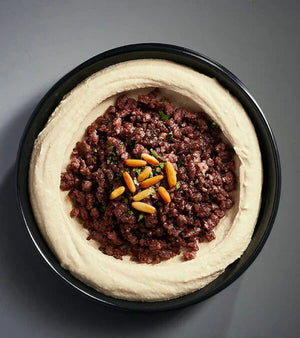 Plant-based hummus with vegan minced topping and pine nuts in a black bowl, iPlantBased UAE