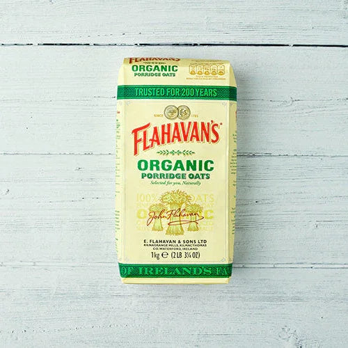 Flahavan's Organic Porridge Oats 1kg pack on a white wooden background, plant-based food