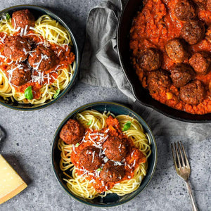 Plant-based spaghetti with vegan meatballs and tomato sauce, topped with shredded cheese